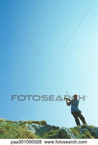 Golfer swinging on rugged terrain View Large Photo Image Stock Photo - Golfer swinging on rugged terrain. Fotosearch