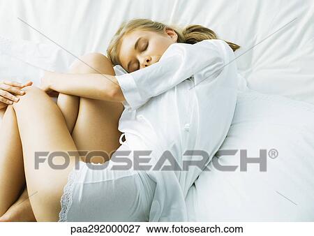 Young woman curled up in bed View Large Photo Image Stock Photo - Young woman curled up in bed. Fotosearch