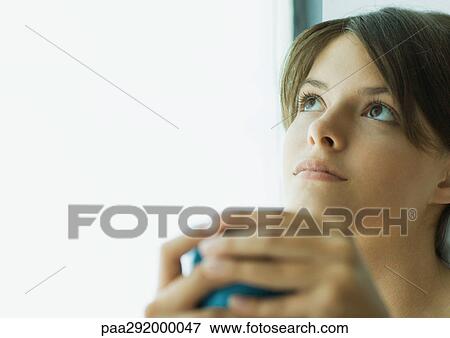 Young woman holding glass, looking up View Large Photo Image Stock Photo - Young woman holding glass, looking up. Fotosearch