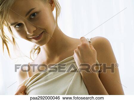 Stock Photograph - Young woman holding up shirt to chest. Fotosearch