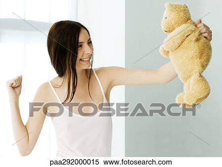 Young woman holding up teddy bear and making fist View Large Photo Image Stock Photography - Young woman holding up teddy bear and making fist. Fotosearch