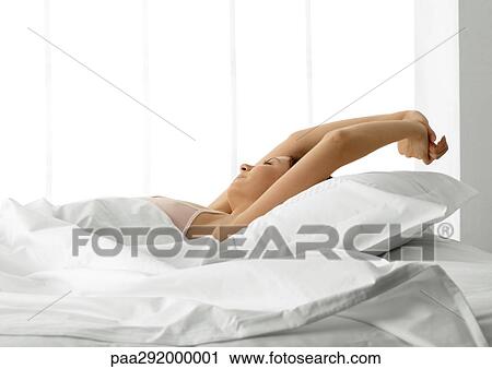 Young woman in bed, stretching arms over head View Large Photo Image Stock Image - Young woman in bed, stretching arms over head. Fotosearch