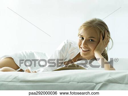 Young woman lounging on bed View Large Photo Image Stock Photograph - Young woman lounging on bed. Fotosearch