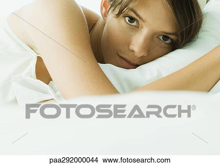 Young woman lying in bed, close-up View Large Photo Image Picture - Young woman lying in bed, close-up. Fotosearch