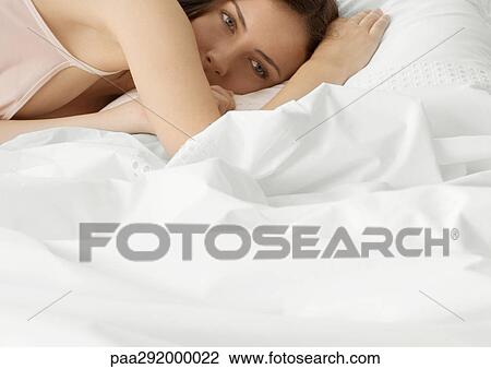 Young woman lying in bed, partial view View Large Photo Image Stock Image - Young woman lying in bed, partial view. Fotosearch