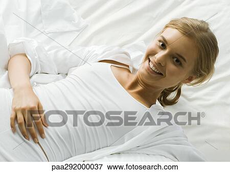 Young woman lying on bed View Large Photo Image Stock Photo - Young woman lying on bed. Fotosearch