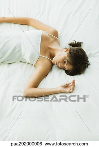 Stock Photograph - Young woman lying on bed. Fotosearch
