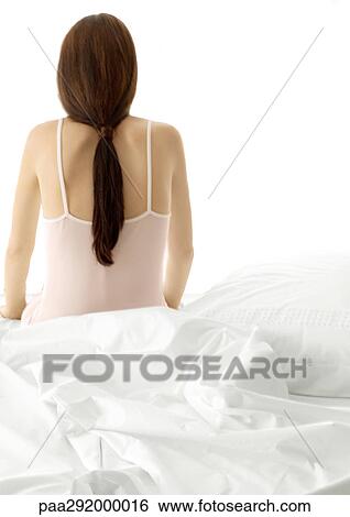 Young woman sitting on edge of bed, rear view View Large Photo Image Stock Photograph - Young woman sitting on edge of bed, rear view. Fotosearch