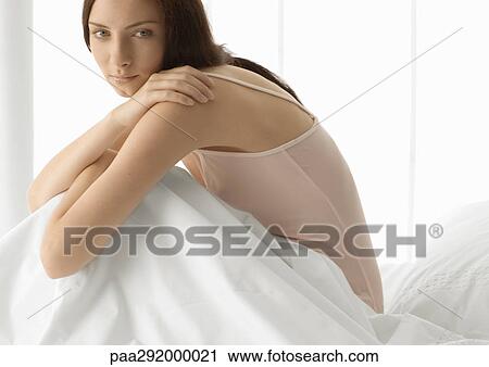 Young woman sitting up in bed, leaning forward View Large Photo Image Stock Image - Young woman sitting up in bed, leaning forward. Fotosearch
