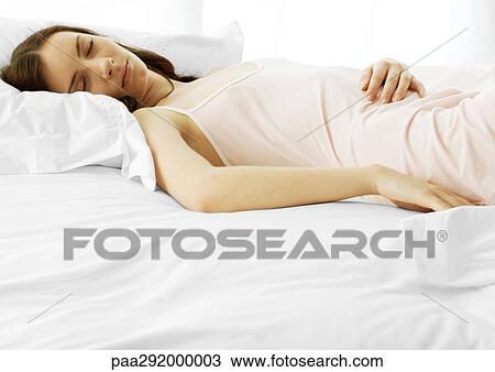 Stock Image - Young woman sleeping on bed. Fotosearch
