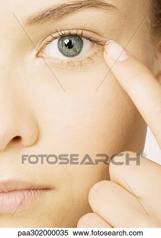 Woman's face with finger next to eye, extreme close-up View Large Photo Image Stock Photography - Woman's face with finger next to eye, extreme close-up. Fotosearch