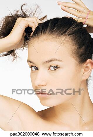 Young woman putting hair in ponytail View Large Photo Image Stock Photo - Young woman putting hair in ponytail. Fotosearch