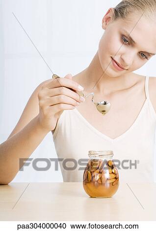 Woman holding spoon over jar of almonds and honey View Large Photo Image Stock Image - Woman holding spoon over jar of almonds and honey. Fotosearch