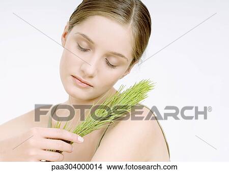 Woman holding sprig of pine, eyes closed View Large Photo Image Picture - Woman holding sprig of pine, eyes closed. Fotosearch