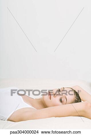 Woman lying back on bed with arms over head View Large Photo Image Picture - Woman lying back on bed with arms over head. Fotosearch