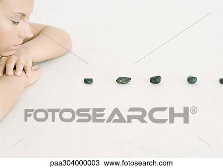 Woman resting head on arms in front of line of stones View Large Photo Image Stock Image - Woman resting head on arms in front of line of stones. Fotosearch