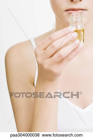 Stock Photo - Woman smelling bottle of essential oil. Fotosearch