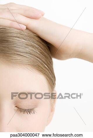 Stock Photo - Woman with hands on head and eyes closed, close-up. Fotosearch