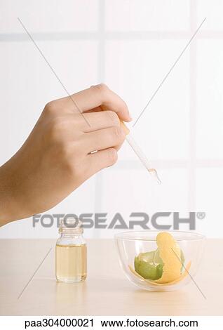 Woman's hand dropping oil into bowl with lemon zest View Large Photo Image Stock Image - Woman's hand dropping oil into bowl with lemon zest. Fotosearch