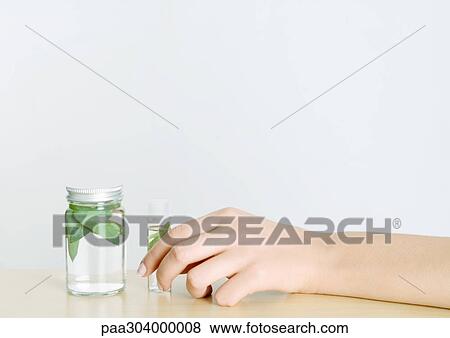 Stock Photo - Woman's hand holding herbal tincture. Fotosearch
