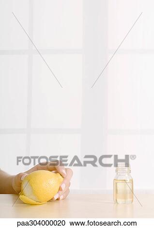 Woman's hand holding lemon next to bottle of essential oil View Large Photo Image Stock Image - Woman's hand holding lemon next to bottle of essential oil. Fotosearch