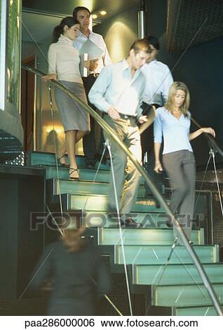 Stock Photograph - Businesspeople walking down stairs together. Fotosearch