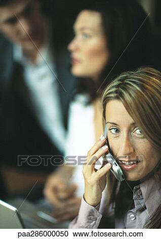 Businesswoman using cell phone in front of two co-workers View Large Photo Image Stock Image - Businesswoman using cell phone in front of two co-workers. Fotosearch