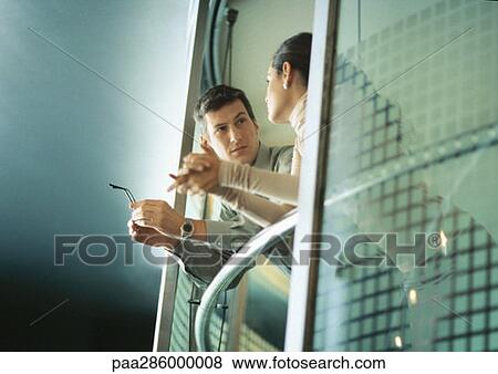 Stock Photo - Man and woman leaning on rail, talking. Fotosearch