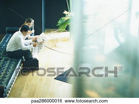 Man and woman sitting on bench in lobby, high angle view View Large Photo Image Stock Photograph - Man and woman sitting on bench in lobby, high angle view. Fotosearch