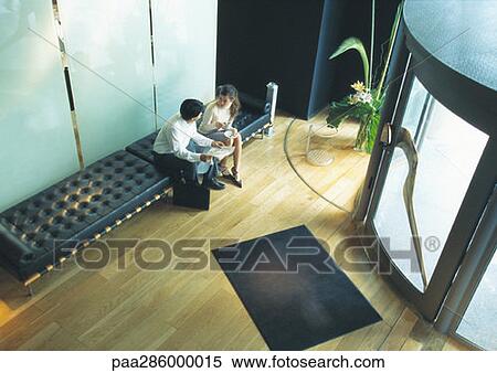 Man and woman sitting on bench in lobby, high angle view View Large Photo Image Stock Photography - Man and woman sitting on bench in lobby, high angle view. Fotosearch