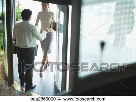 Picture - Man standing in doorway as woman enters. Fotosearch