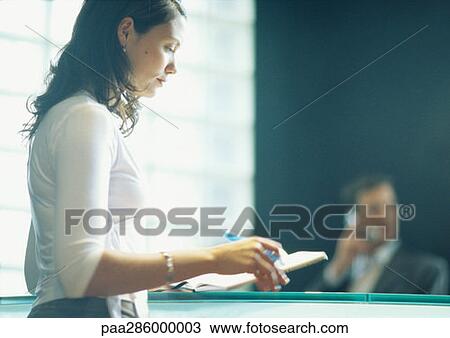 Woman in office, man on phone in background View Large Photo Image Stock Image - Woman in office, man on phone in background. Fotosearch
