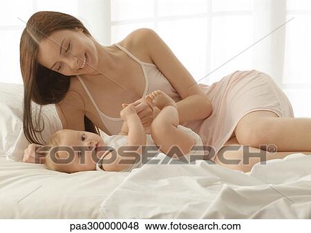 Stock Photo - Baby and mother on bed. Fotosearch