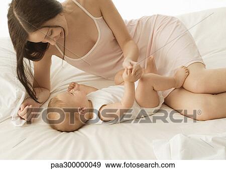 Baby and mother on bed View Large Photo Image Stock Photo - Baby and mother on bed. Fotosearch