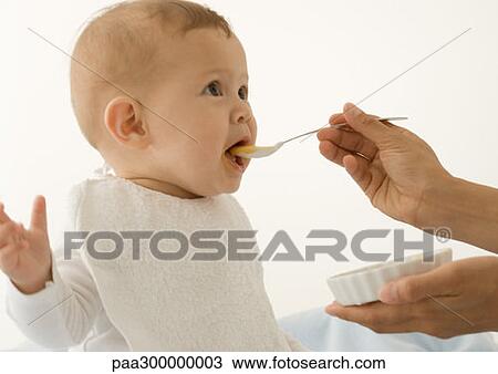 Stock Image - Baby being fed baby food. Fotosearch