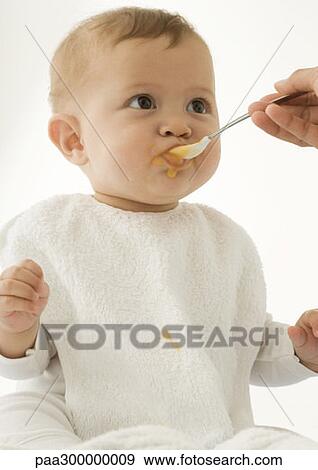 Baby being fed baby food View Large Photo Image Stock Photo - Baby being fed baby food. Fotosearch