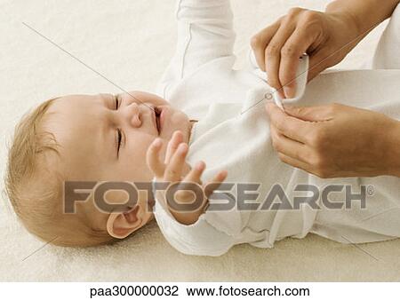 Stock Image - Baby getting dressed. Fotosearch