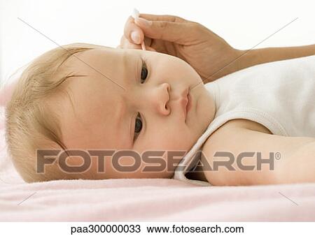 Stock Image - Baby having ear cleaned. Fotosearch