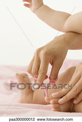 Stock Image - Baby having toenails cut. Fotosearch