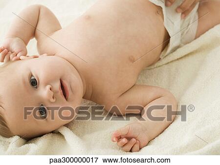 Stock Photo - Baby lying on back, looking at camera. Fotosearch