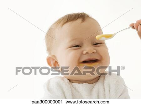 Smiling baby being fed baby food View Large Photo Image Stock Image - Smiling baby being fed baby food. Fotosearch