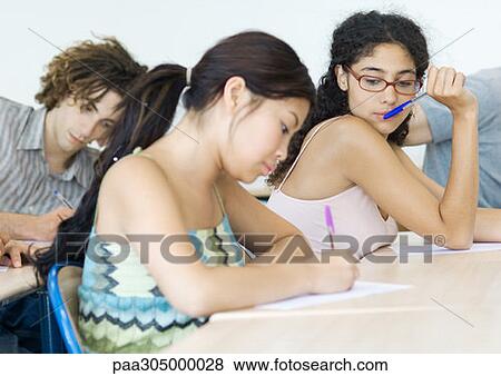 Stock Photo - Students taking test in class, one student looking at another's paper. Fotosearch