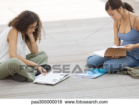 Two students sitting on ground, studying View Large Photo Image Stock Photo - Two students sitting on ground, studying. Fotosearch