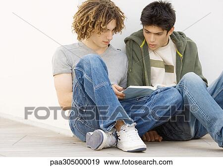 Two students sitting on ground studying together View Large Photo Image Stock Photo - Two students sitting on ground studying together. Fotosearch
