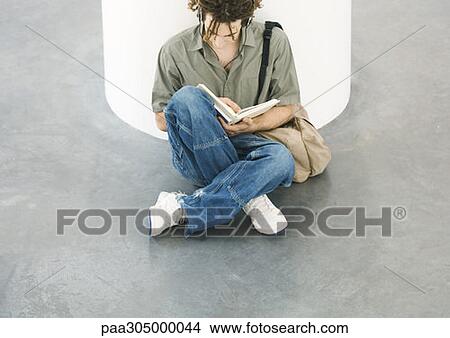 Young man sitting on floor, reading View Large Photo Image Picture - Young man sitting on floor, reading. Fotosearch