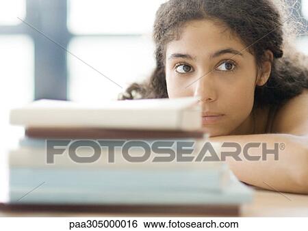 Young woman resting head on arms, behind pile of books View Large Photo Image Stock Photograph - Young woman resting head on arms, behind pile of books. Fotosearch