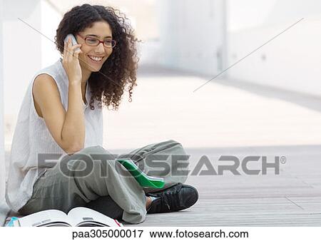Young woman sitting indian style on ground, talking on cell phone View Large Photo Image Stock Photo - Young woman sitting indian style on ground, talking on cell phone. Fotosearch