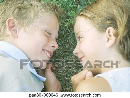 Stock Photograph - Boy and girl lying in grass, smiling. Fotosearch