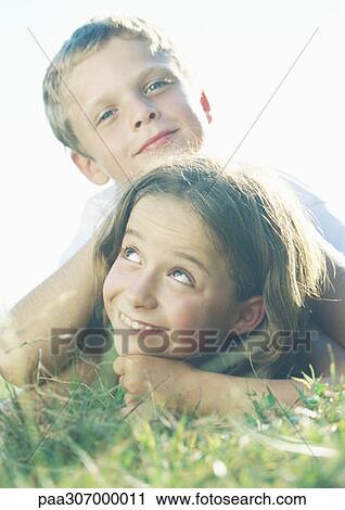 Boy and girl lying in grass View Large Photo Image Stock Image - Boy and girl lying in grass. Fotosearch