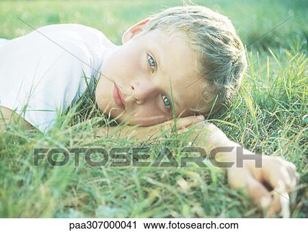 Boy lying in grass View Large Photo Image Stock Image - Boy lying in grass. Fotosearch